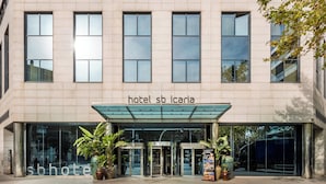 L’entrée d’un hôtel avec une façade en verre, un espace d’entrée abrité et des plantes en pot.