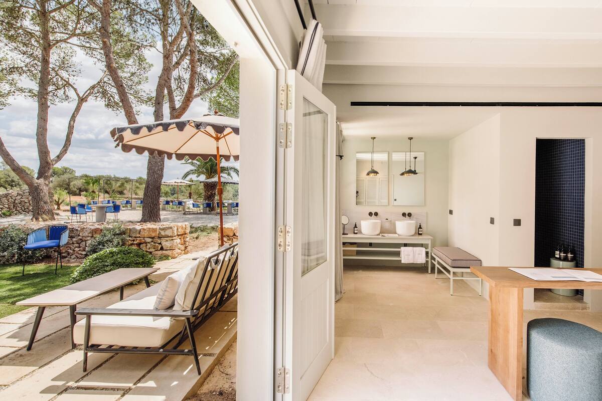 Een moderne keuken met een groot eiland, een eethoek met tafel en stoelen, en uitzicht op het buitenterras met zitplaatsen en parasols.