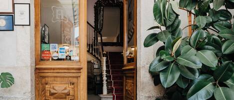 A wooden door with a mirror, a staircase, and a plant.