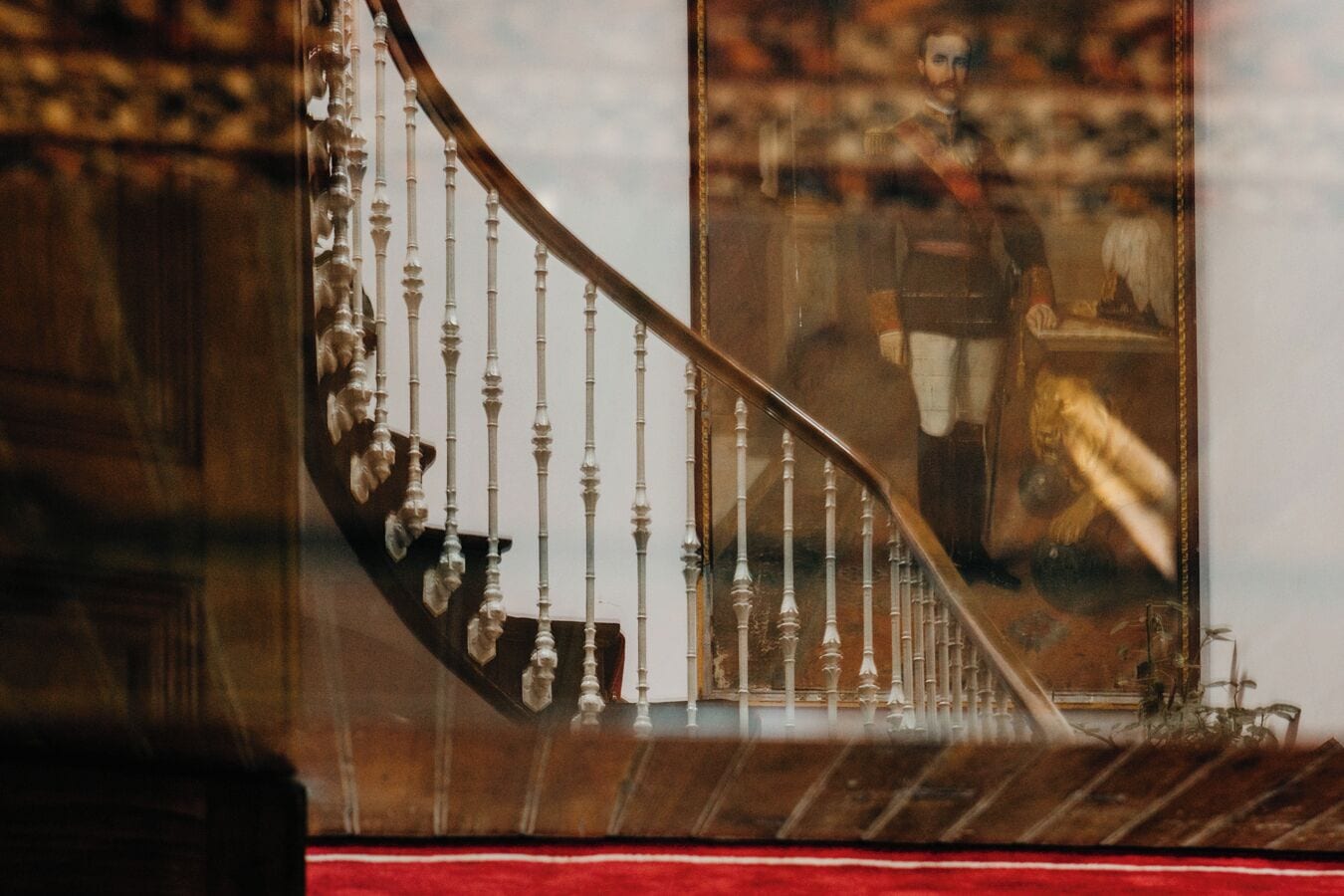 A staircase with ornate balusters and a painting of a historical figure.