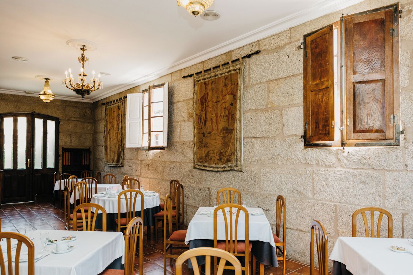 A dining area with stone walls, wooden tables, and chairs.