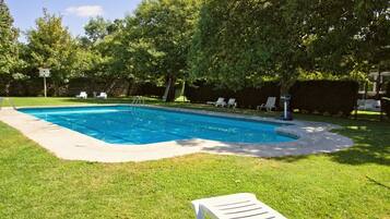 Una piscina al aire libre de temporada, tumbonas