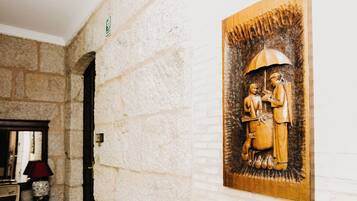 Un muro de piedra con un relieve de madera tallada que muestra dos figuras, una lámpara y una radio antigua.