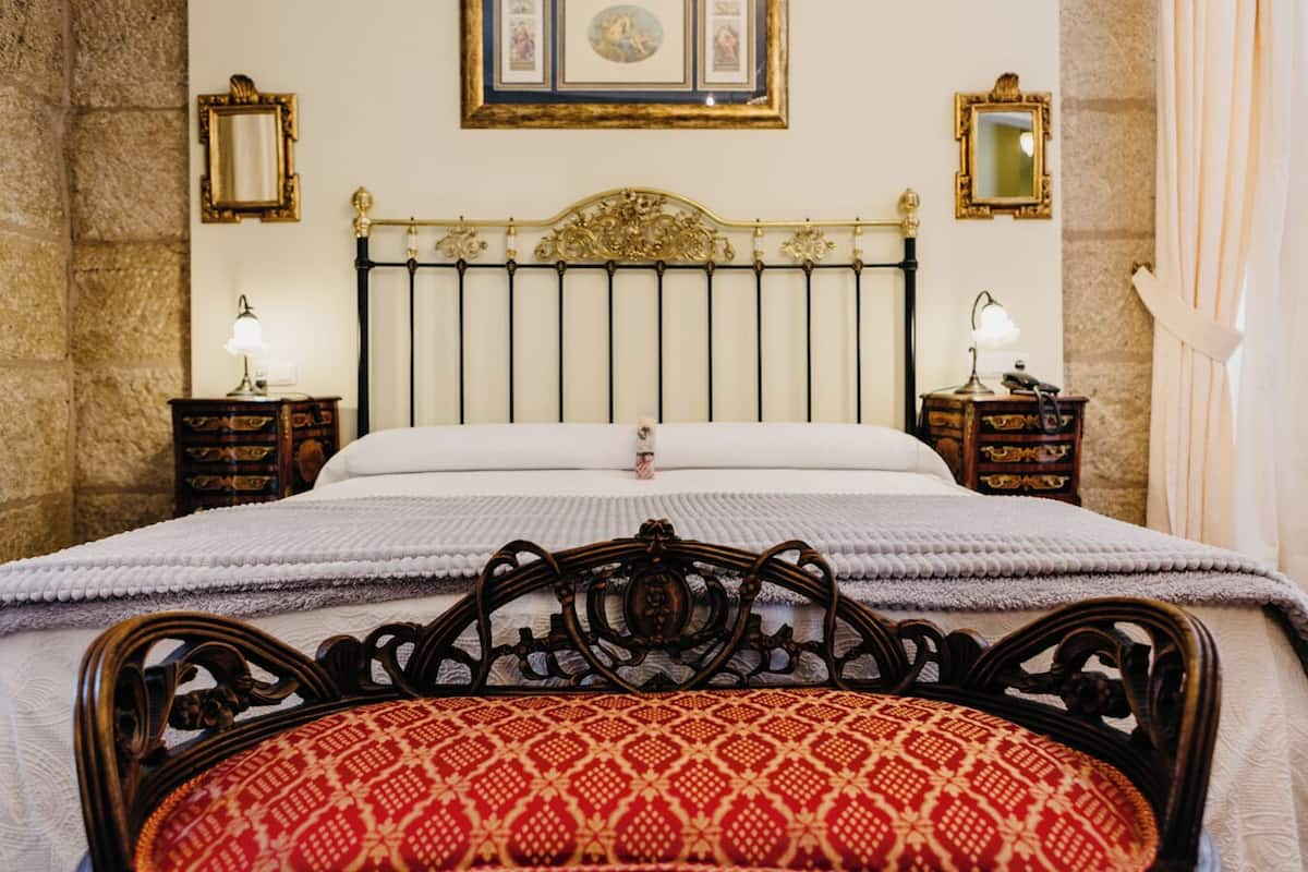 A bed with a headboard, two bedside tables with lamps, and a wall with framed pictures.