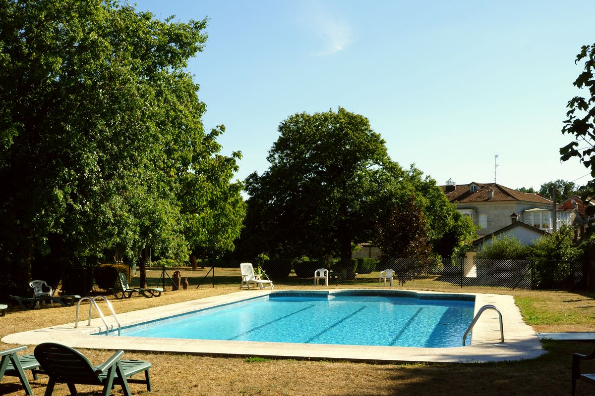 Een seizoensgebonden buitenzwembad, ligstoelen bij het zwembad