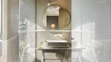A modern bathroom with a round mirror, a marble sink, and a shower with a glass enclosure.