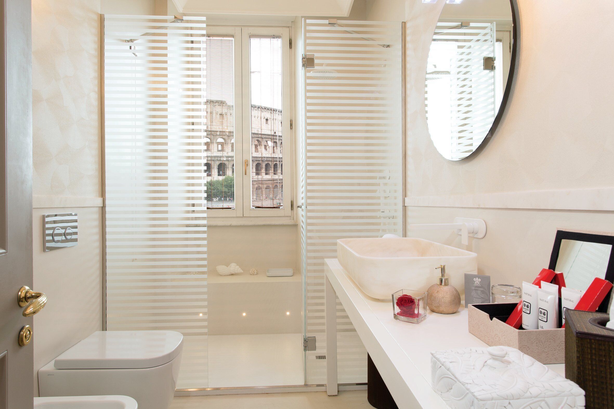 A modern bathroom with a glass-enclosed shower, a large vessel sink, and a vanity with toiletries.