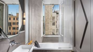 Un baño moderno con un espejo grande, una bañera y un ventanal con vistas a edificios.