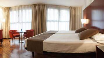 Habitación de hotel con dos camas, un escritorio con silla, televisor y lámpara.