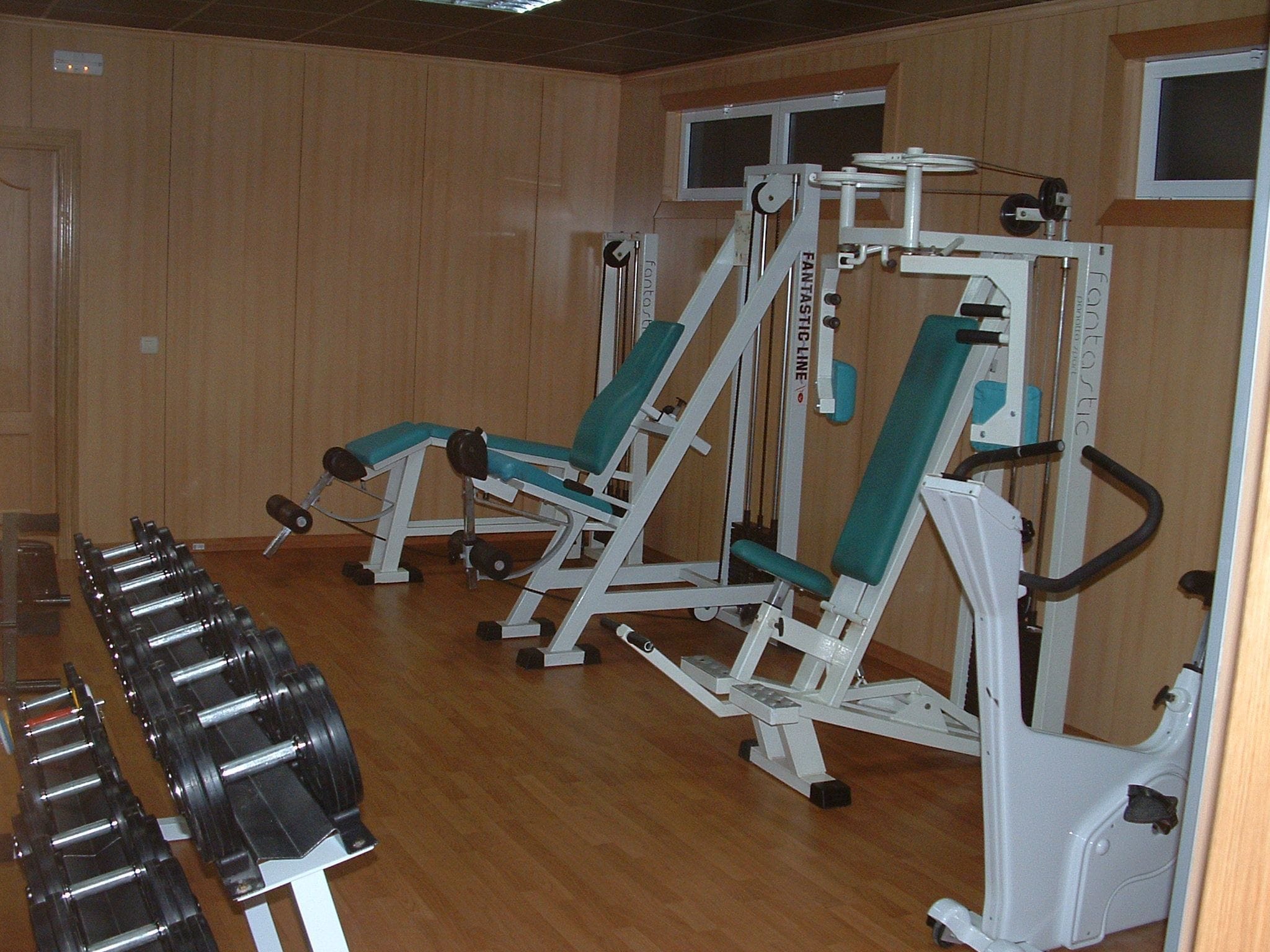 A gym with weight machines and dumbbells.