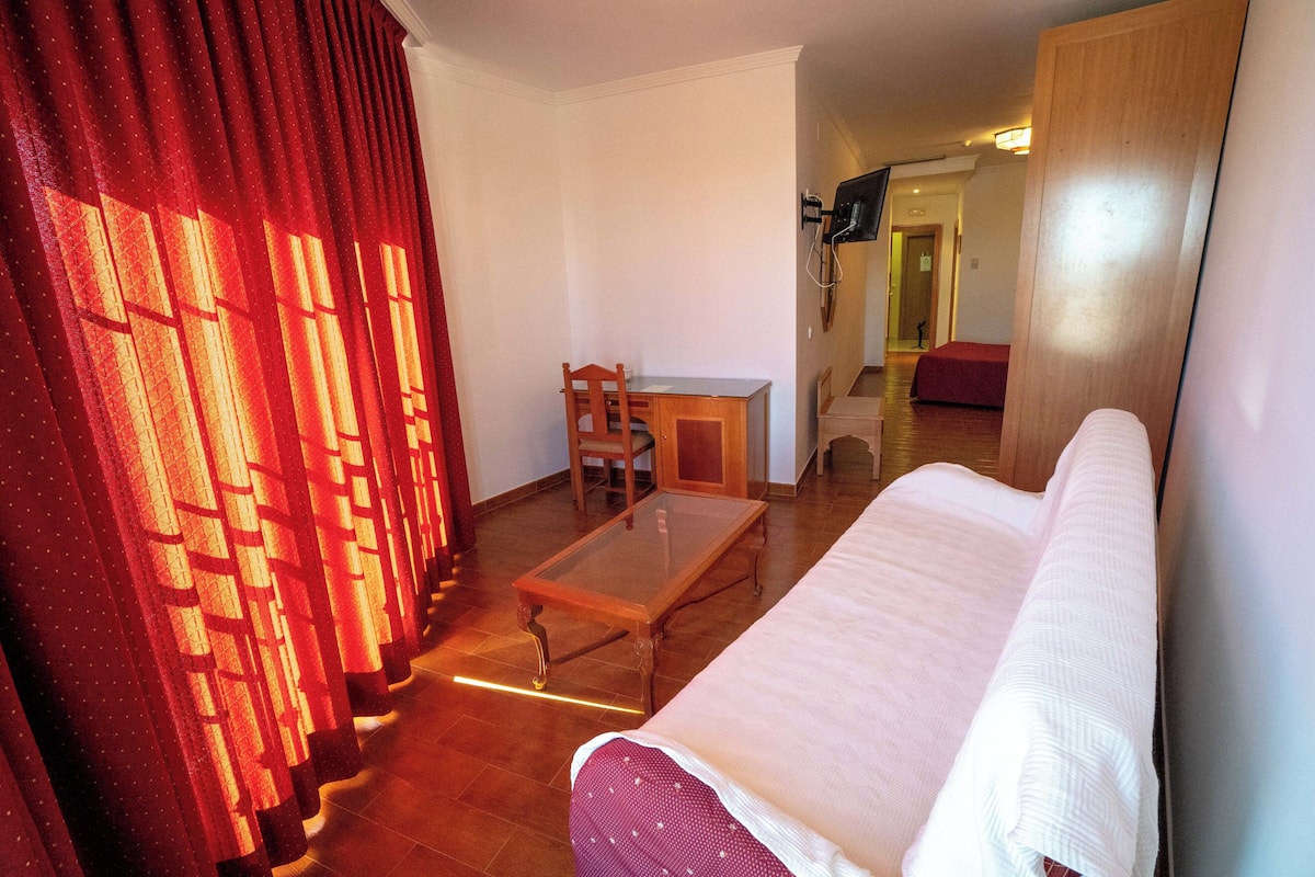 Une pièce comprenant un lit, une table en bois, une chaise et un bureau.