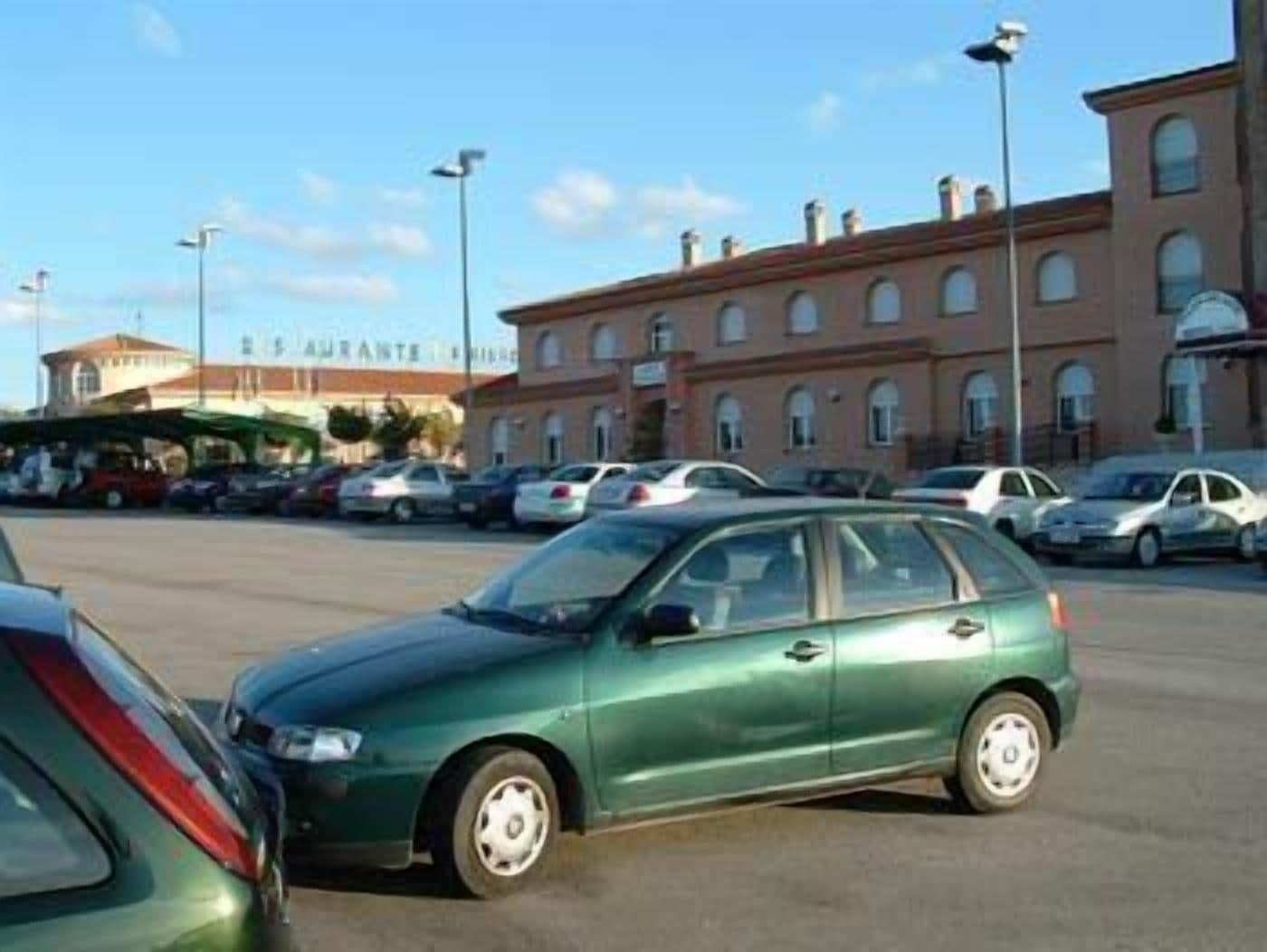 A parking lot with several cars, a building with arched windows, and a sign that reads "Ristorante".