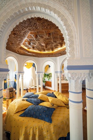A room with a large bed, ornate ceiling, and white columns. - Hotel Villa de Gor (Gor)