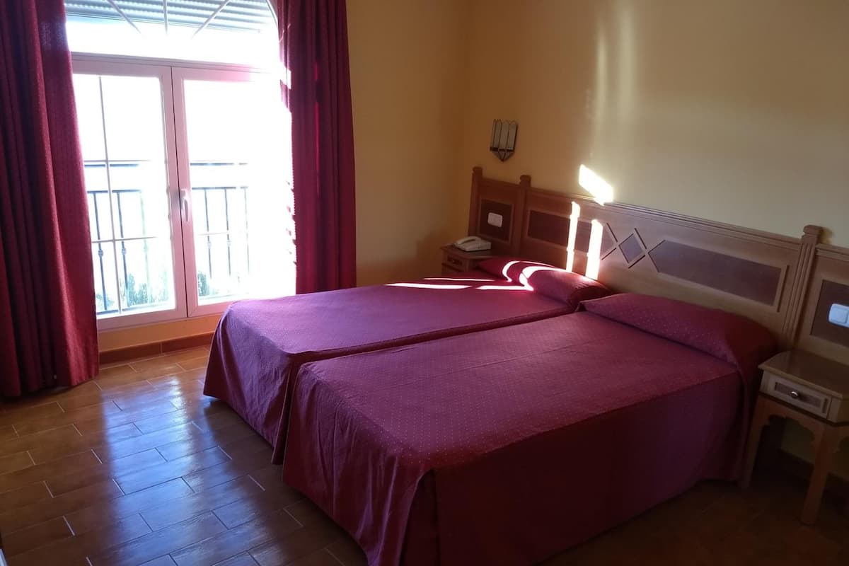 Un lit double avec une tête de lit en bois, une table de chevet et une petite table avec une lampe.
