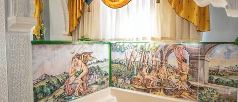 Un baño con una bañera grande, techo ornamentado y azulejos decorativos.