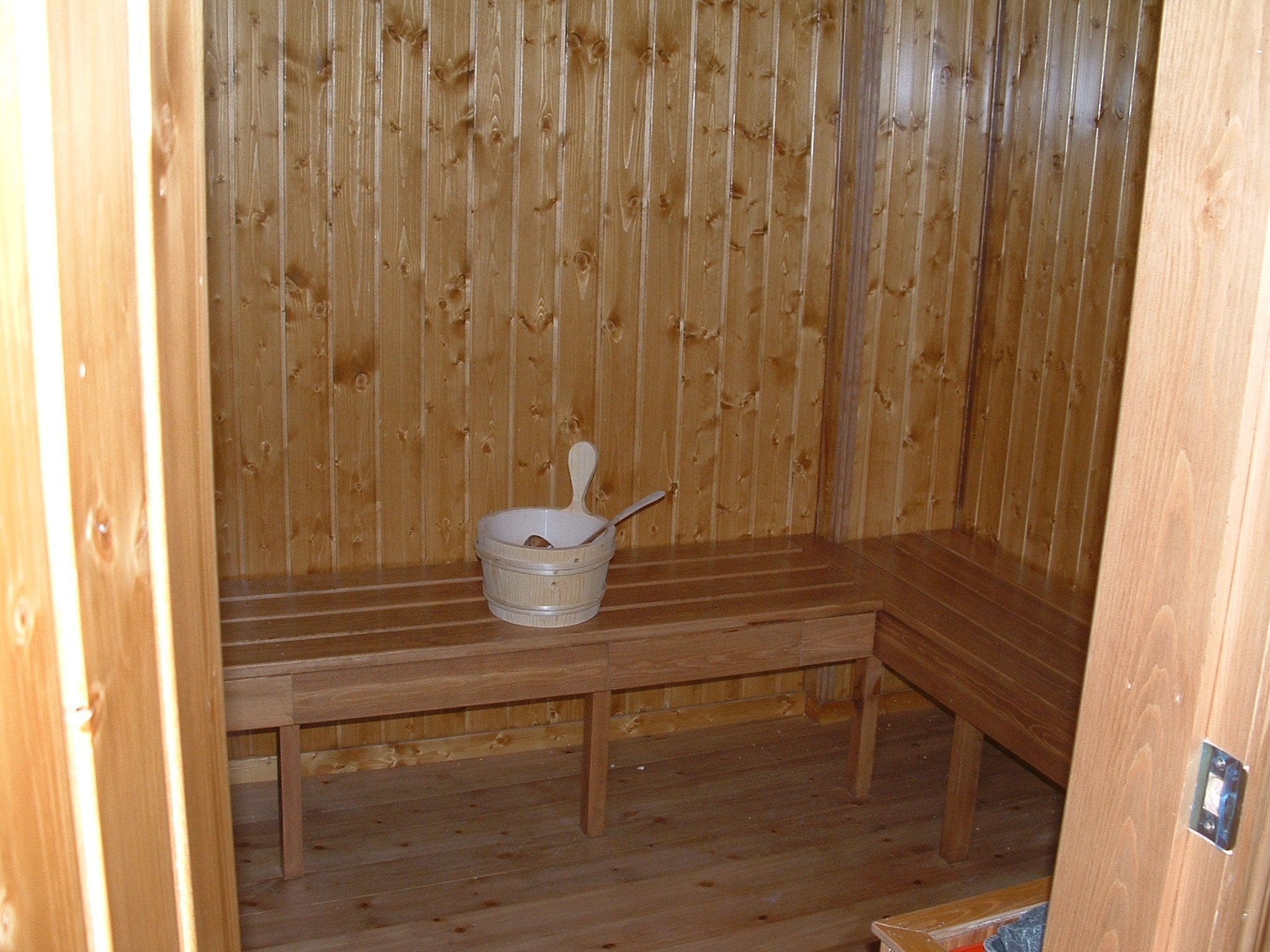 A wooden sauna with a bench and a bucket.