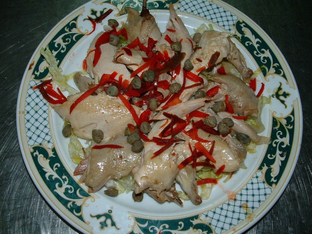 A plate of chicken with red peppers and capers.