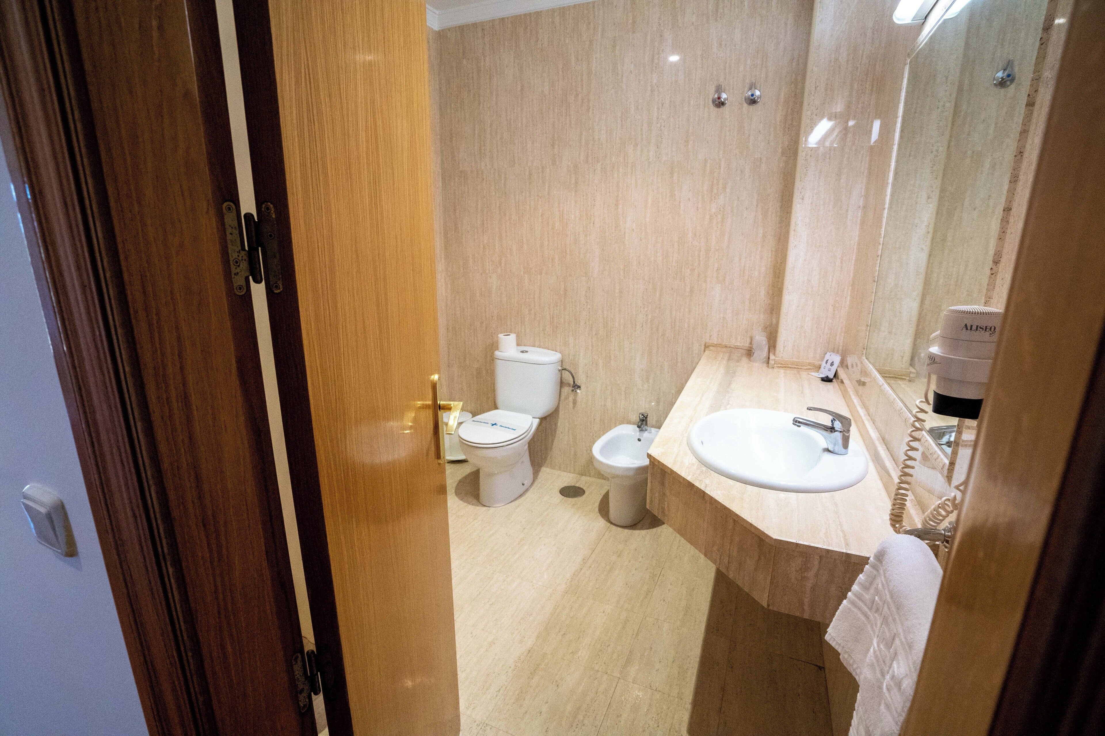 Une salle de bain équipée de toilettes, d’un bidet et d’un lavabo.