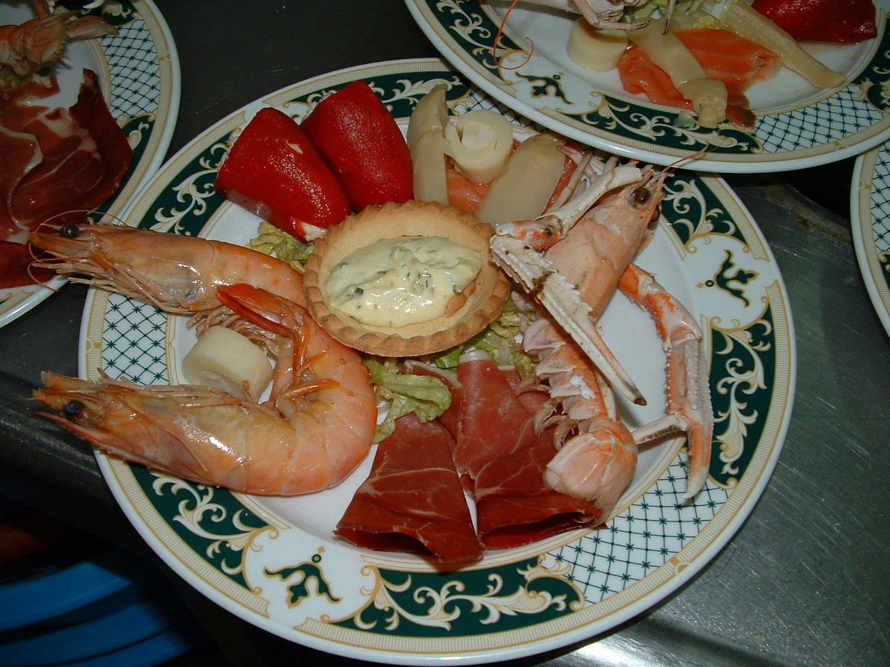 A plate with shrimp, prosciutto, and a tart.