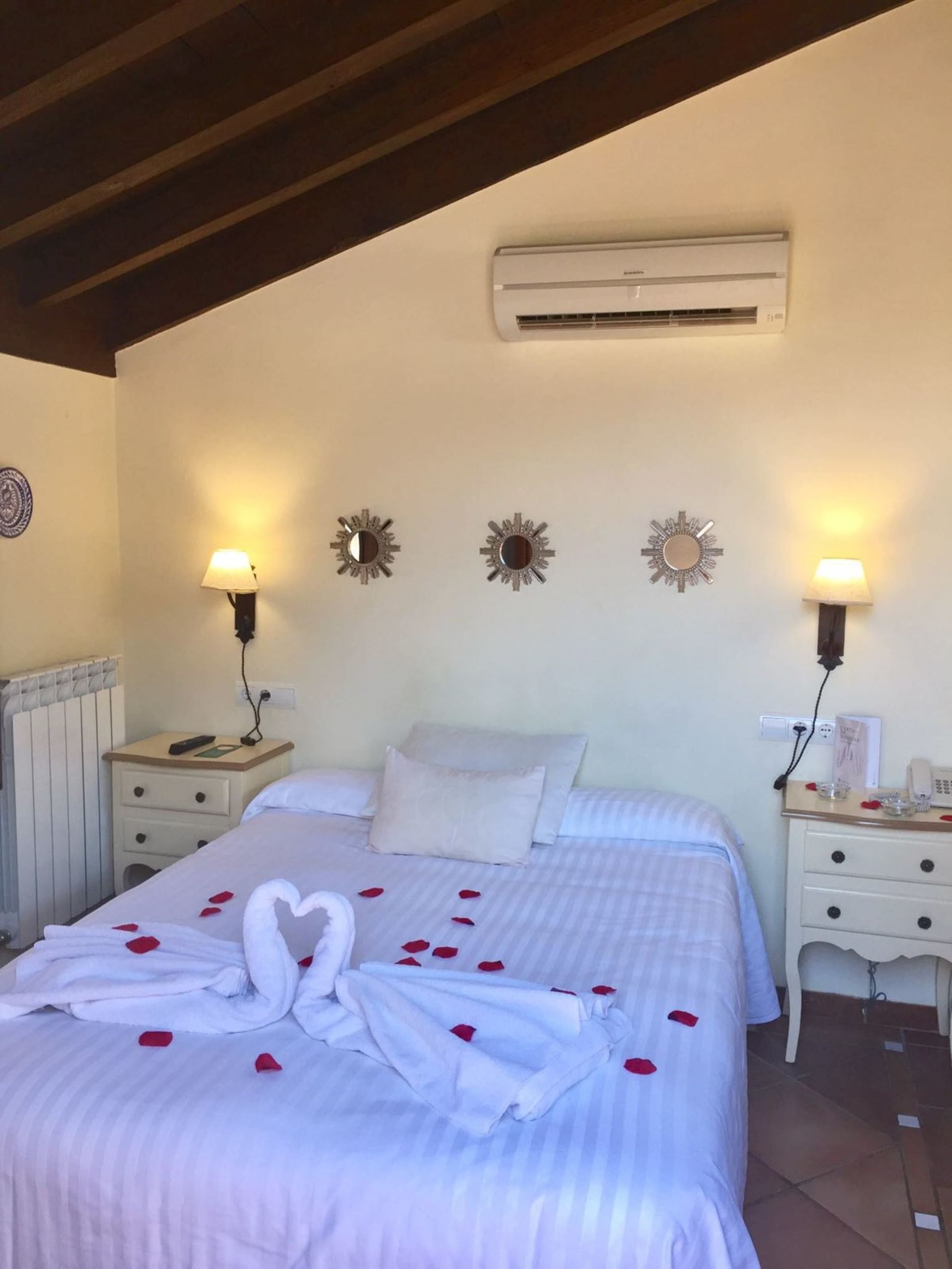 Hotelkamer met een bed, nachtkastjes, wandairconditioning, decoratieve wandlampen en een radiator.