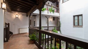 A covered balcony with wooden railings, potted plants, and white walls. - Casa del Capitel Nazari Hotel (Granada)