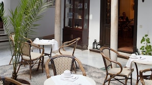 A courtyard with wicker furniture, a central column, and a dining area. - Casa del Capitel Nazari Hotel (Granada)