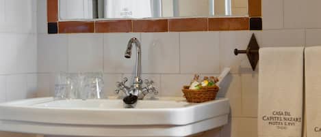 A bathroom with a white sink, a mirror, and a towel hanging on the wall.
