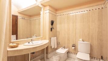 A bathroom with a sink, mirror, toilet, and bidet.