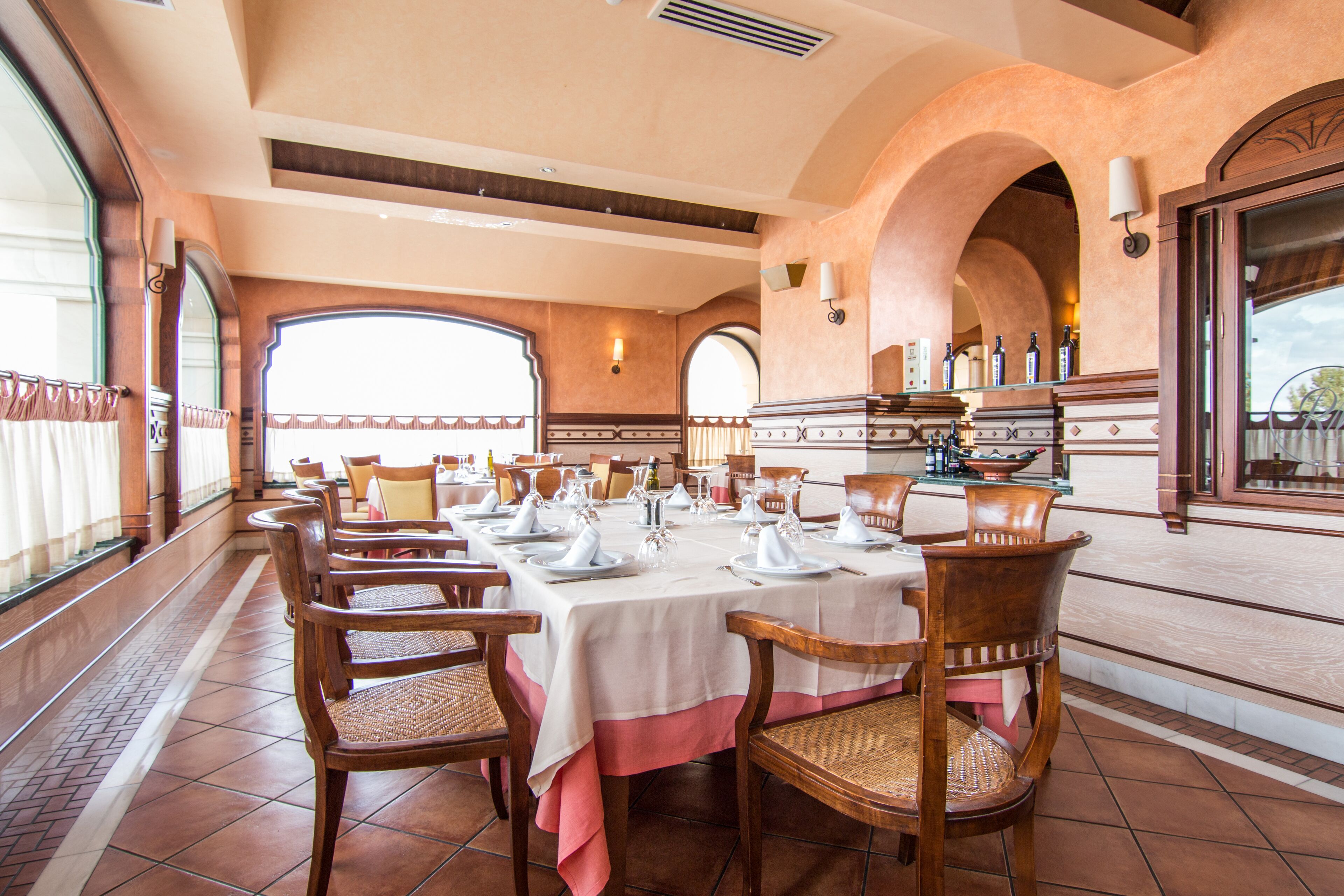 A dining area with a long table set for a meal, surrounded by wooden chairs with woven seats.