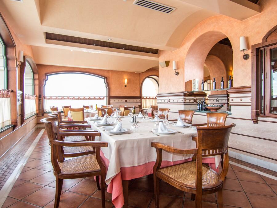 A dining area with a long table set for a meal, surrounded by wooden chairs with woven seats.