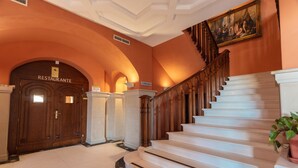 Una gran escalera con barandilla de madera y peldaños blancos que conducen a una puerta con la leyenda "RESTAURANTE".