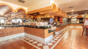 Un área de comidas autoservicio con mostrador, vitrina refrigerada y diversas opciones de alimentos.