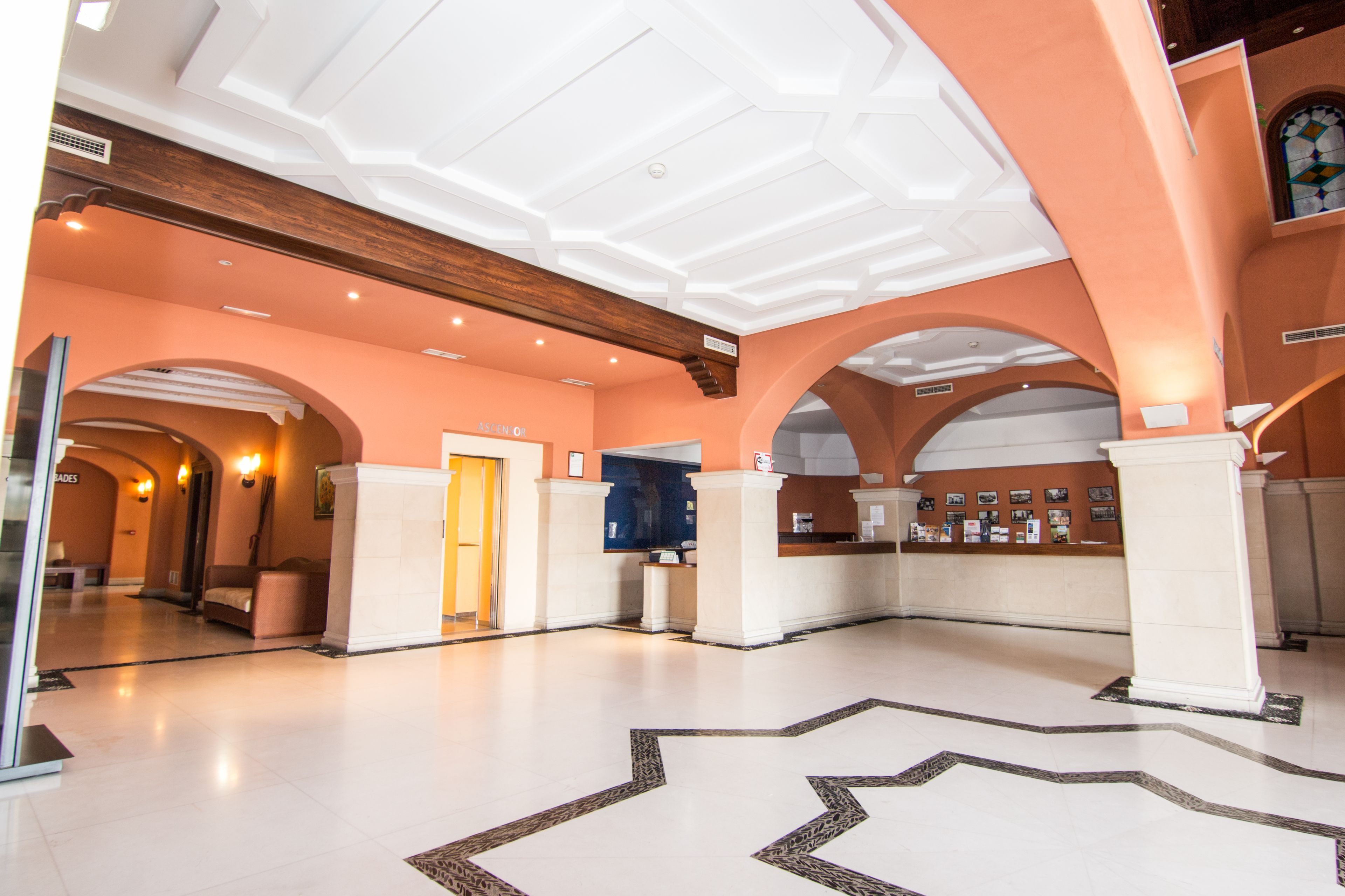 A spacious lobby with high ceilings, arched doorways, and a central reception desk.
