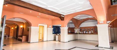 A spacious lobby with high ceilings, arched doorways, and a central reception desk.