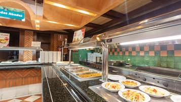 A buffet area with multiple food stations and a tiled backsplash.