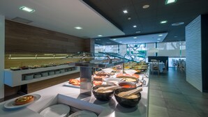 A buffet area with various food stations and a seating area with tables and chairs. - Hotel California Palace (Salou)