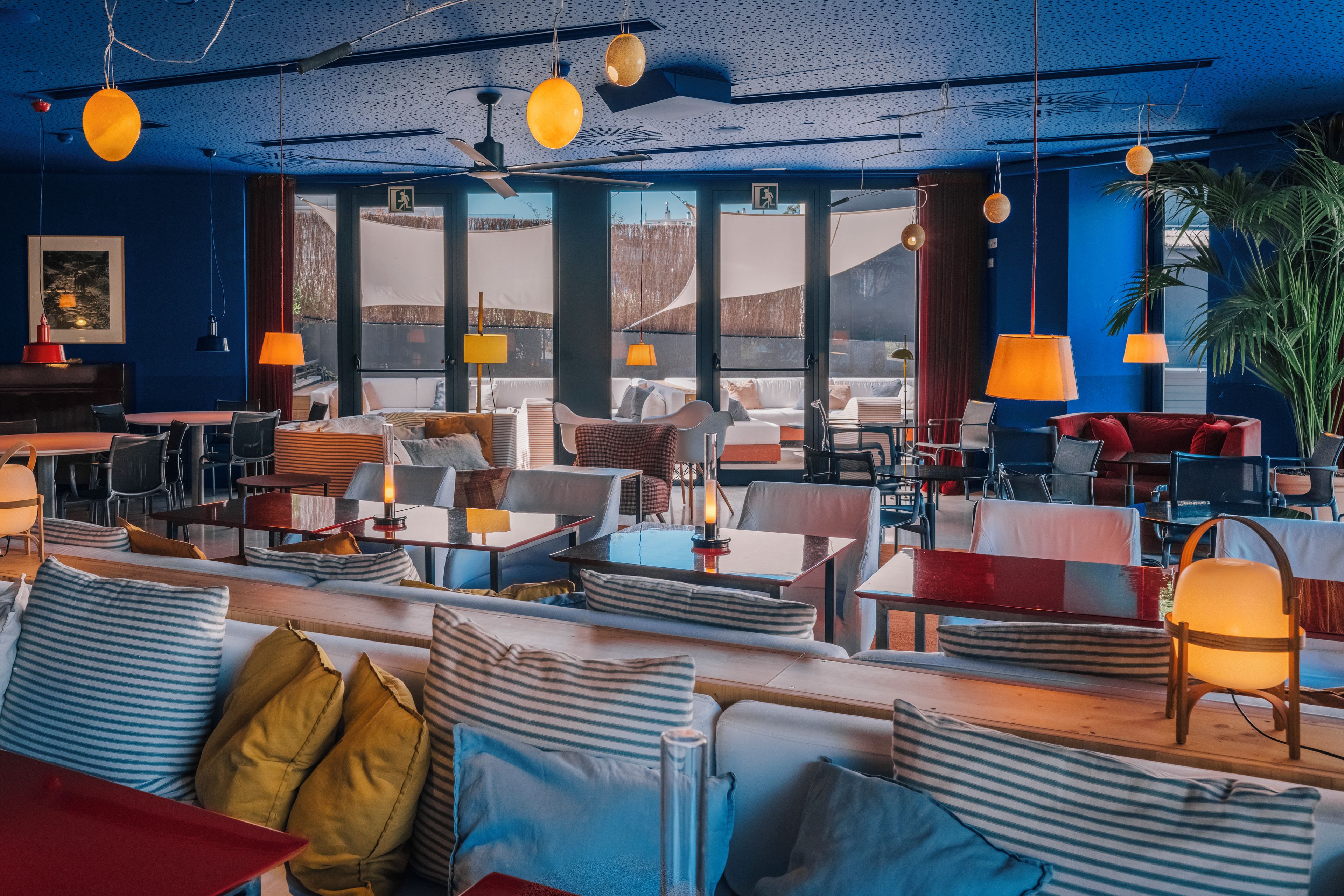 Un restaurante moderno con una decoración azul y amarilla, que ofrece una variedad de opciones de asientos, incluyendo mesas, sillas y sofás.