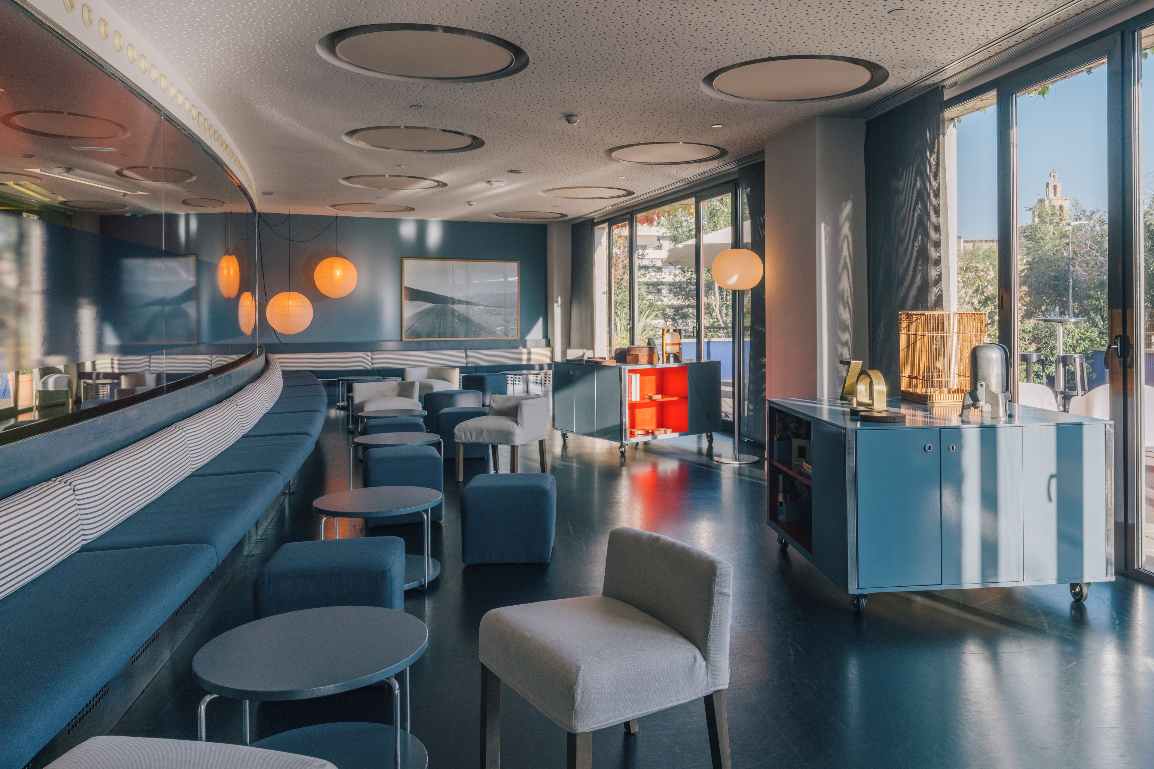 Un restaurante moderno con una zona de asientos curva, mesas redondas y una barra.