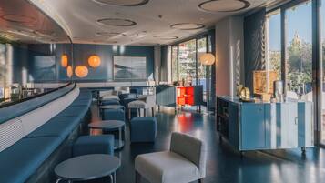 Un restaurante moderno con una zona de asientos curva, mesas redondas y una barra.