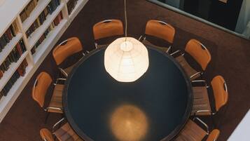 Une table ronde entourée de huit chaises, elle-même entourée d’étagères, dans un intérieur moderne.