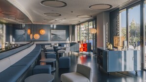 Un restaurant modern amb una zona de seients corbada, taules rodones i una barra.