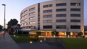 Un edifici d'hotel modern amb façana corbada, diverses plantes i un senyalitzador ben visible per a "STCHR".