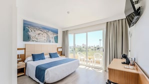 A hotel room with a large bed, a desk, a TV mounted on the wall, and a balcony with a view of the city. - Hospedium Hotel Abril (San Juan de Alicante)