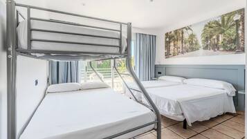 Un dormitorio con camas literas, un cuadro de paisaje tropical y vista a zonas verdes.