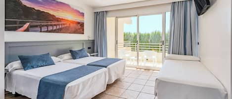 Quarto de hotel com duas camas, televisão, varanda com vista para a floresta e uma pintura de pôr do sol na parede.