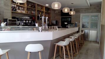 Un área de bar moderna con una barra larga, taburetes y una variedad de botellas.