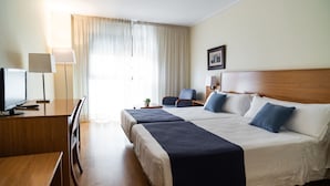 A hotel room with two beds, a desk, a chair, a lamp, and a window with curtains. - Hotel Villa San Juan (San Juan de Alicante)