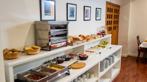 A buffet setup with various food items and a bread display. - Hotel Villa San Juan (San Juan de Alicante)
