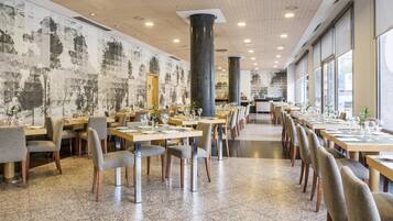 A spacious restaurant with high ceilings, large windows, and a modern interior design.
