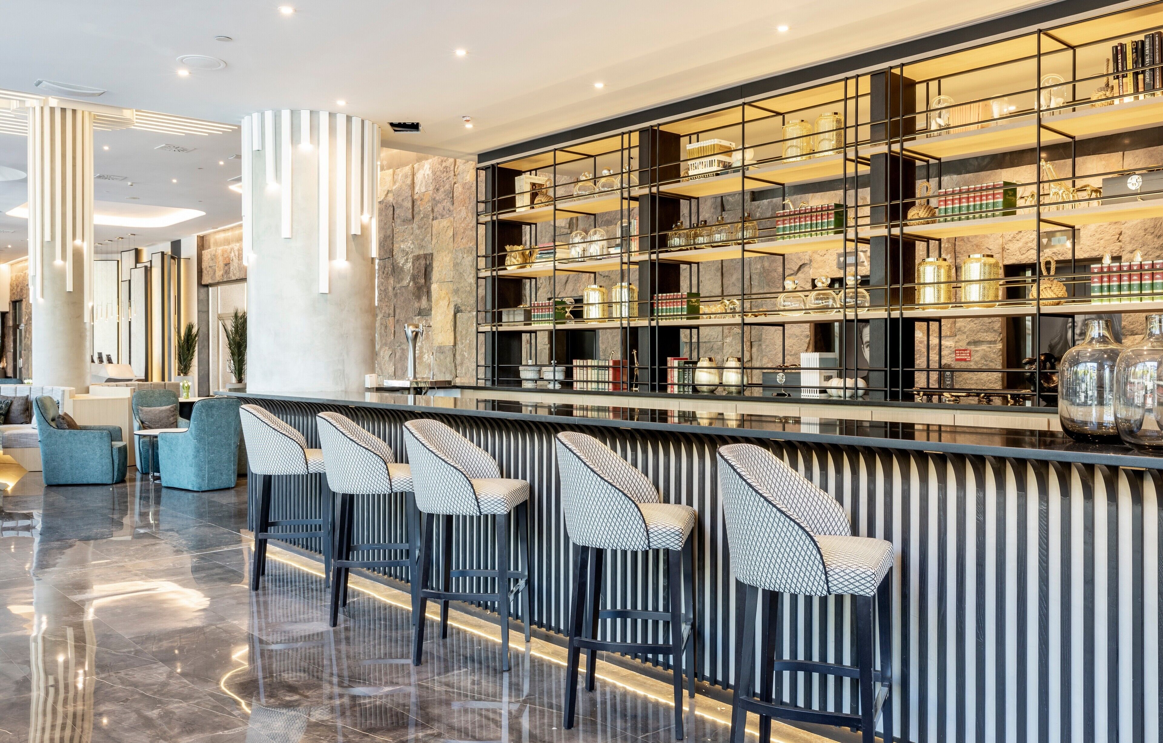 A modern bar area with high stools and a display of glassware.